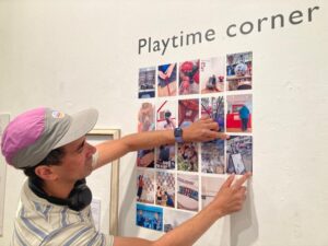 Gallery wall covered in small printed photographs taken by festival visitors